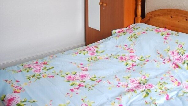 A bedroom with a bed, a wooden wardrobe, a door, and a ceiling light. - Clift Guest House (Bristol)