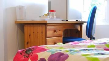 A bedroom with a bed, a desk with a computer, and a chair.