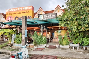 A guest house with a signboard, outdoor seating, and potted plants. - OYO 75304 Riverside Guesthouse (Takua Pa)