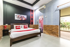 A hotel room with a bed, a nightstand, a red lamp, a painting on the wall, and a view of the outside. - OYO 75304 Riverside Guesthouse (Takua Pa)