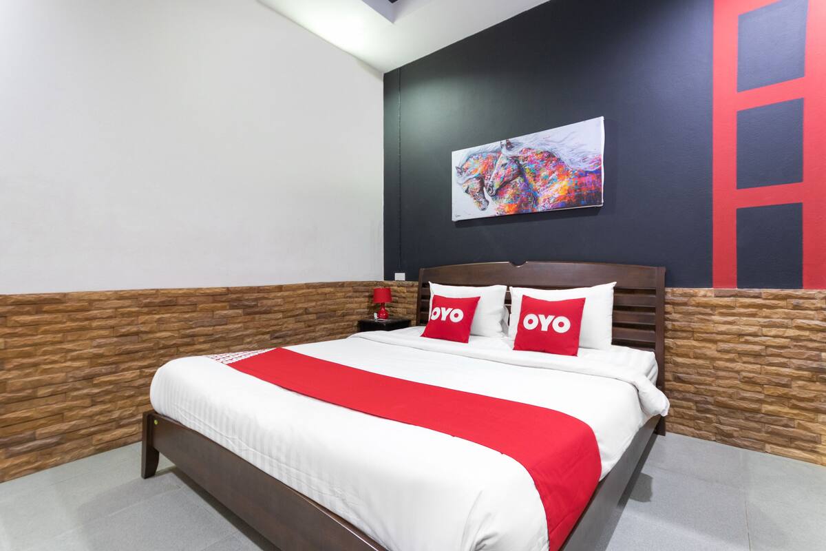 A neatly made bed with a red and white bedspread and two pillows with the word "OYO" on them.