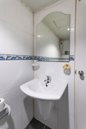 A bathroom with white tiled walls, a white sink, a mirror, and a shower. - OYO 75304 Riverside Guesthouse (Takua Pa)