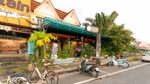 A guest house with a covered entrance, a bicycle, and a scooter parked outside. - OYO 75304 Riverside Guesthouse (Takua Pa)