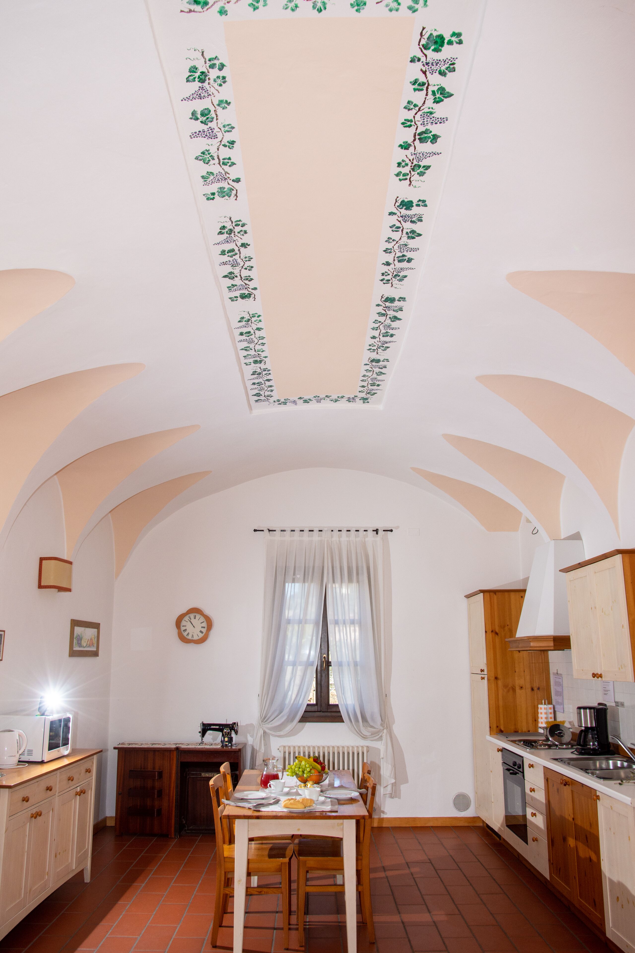 A kitchen with a dining table, chairs, a clock, and a radiator.