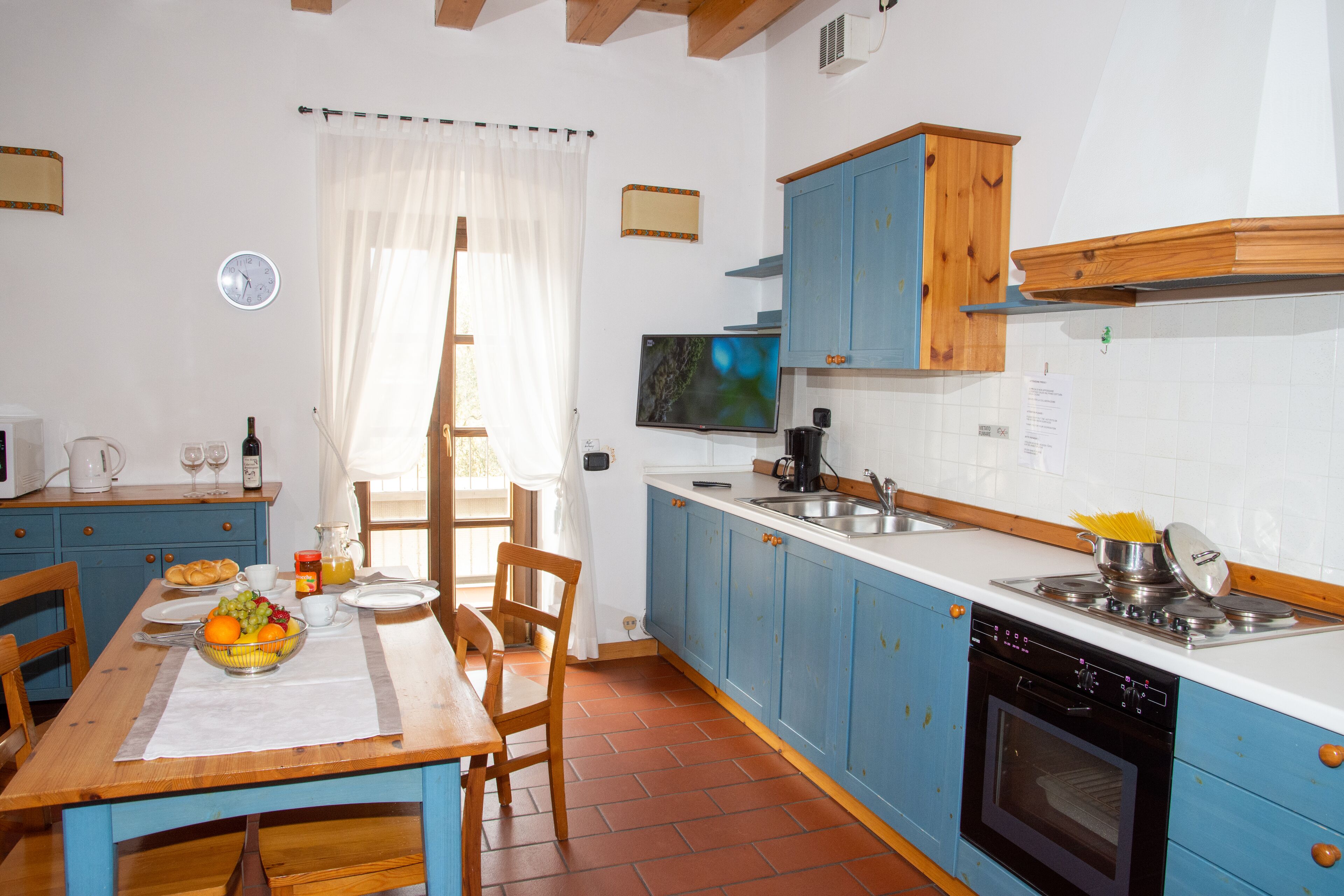 A kitchen with blue cabinets, a wooden table, and a tiled backsplash.