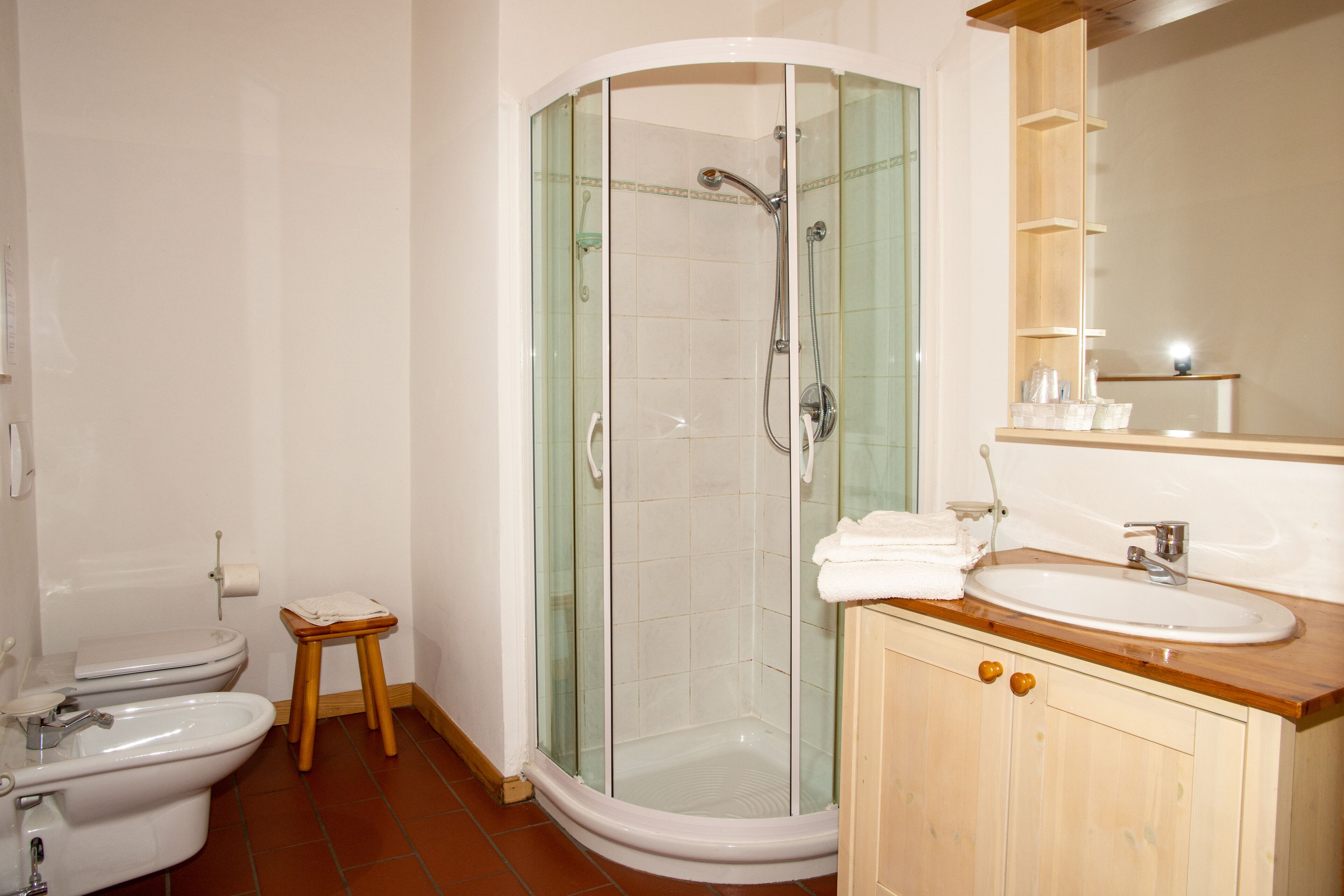 A bathroom with a glass-enclosed shower, a wooden vanity with a sink, and a toilet.