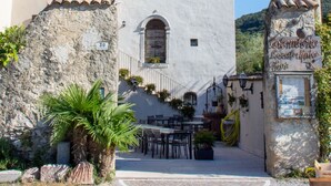 Un bâtiment à la façade blanche, doté d’un toit en tuiles et d’un mur en pierre sur lequel est apposée une enseigne.