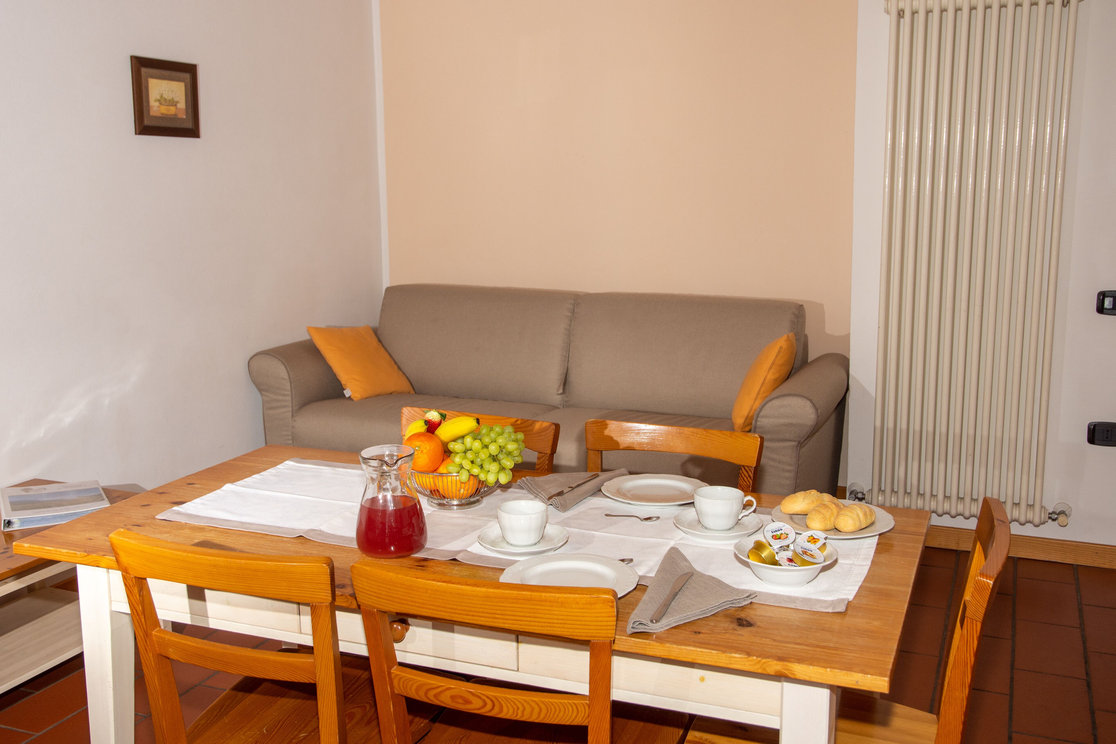 Comedor con una mesa de madera dispuesta para el desayuno, incluyendo platos, tazas y un frutero.