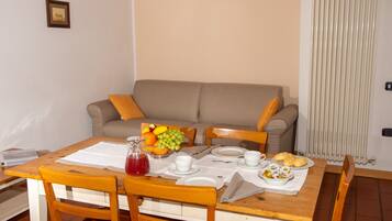 Comedor con una mesa de madera dispuesta para el desayuno, incluyendo platos, tazas y un frutero.