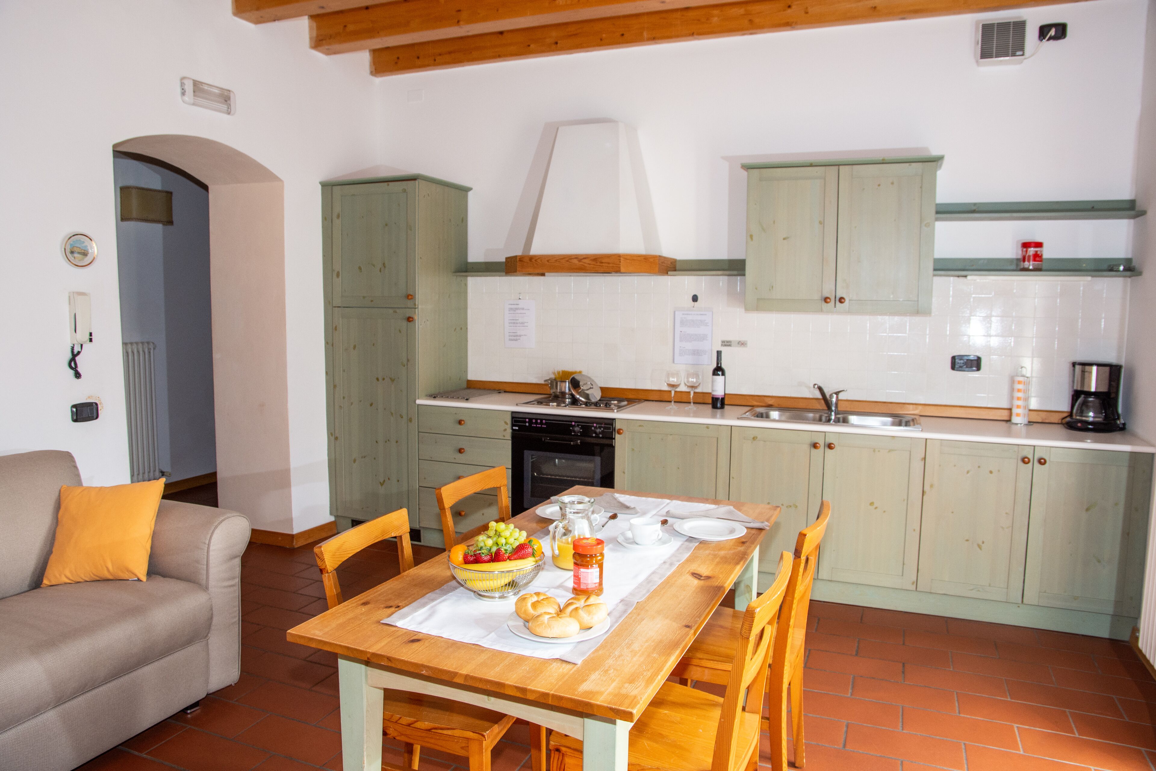 A compact kitchen with a dining table, chairs, and a sofa in a cozy living area.