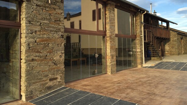 A stone building with large glass windows, a wooden staircase, and a metal roof. - Pazo Torre do Barrio (Sarria)