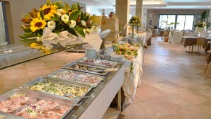 Montaje tipo bufé con diversas opciones de comida y un centro de mesa floral.