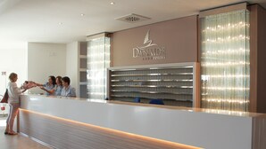 Una recepción en el Danaide Resort con diseño moderno, un logotipo sobre la mesa y una partición de vidrio con luces.