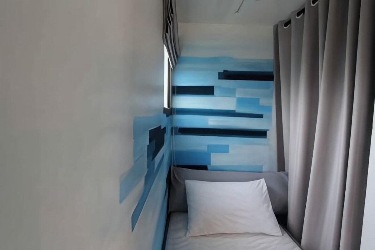 Une pièce avec un lit, une fenêtre et un mur orné d’un motif géométrique.