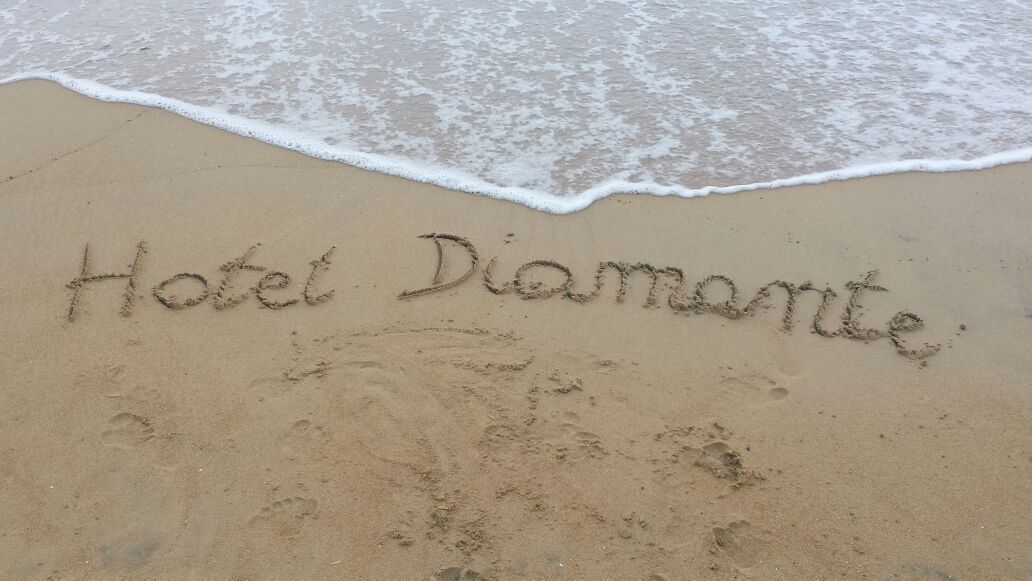 Una spiaggia con la scritta "Hotel Diamante" tracciata sulla sabbia.