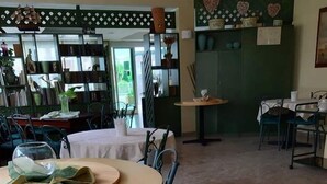 Un comedor con mesas redondas, sillas y una vela de vidrio sobre una mesa.