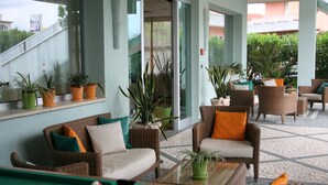 Zona de piscina con mobiliario de mimbre, mesa de billar y plantas en macetas.