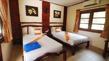 A room with two wooden beds, a window, and an air conditioning unit.