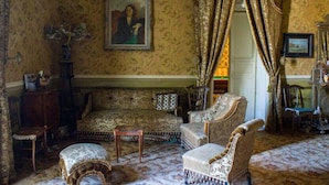 A traditional room with patterned wallpaper, a sofa, armchairs, a small table, and a decorative vase. - Giardino di Pietra (Ragusa)