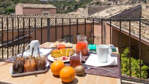 A breakfast table with various food items and drinks on a balcony overlooking a cityscape. - Giardino di Pietra (Ragusa)