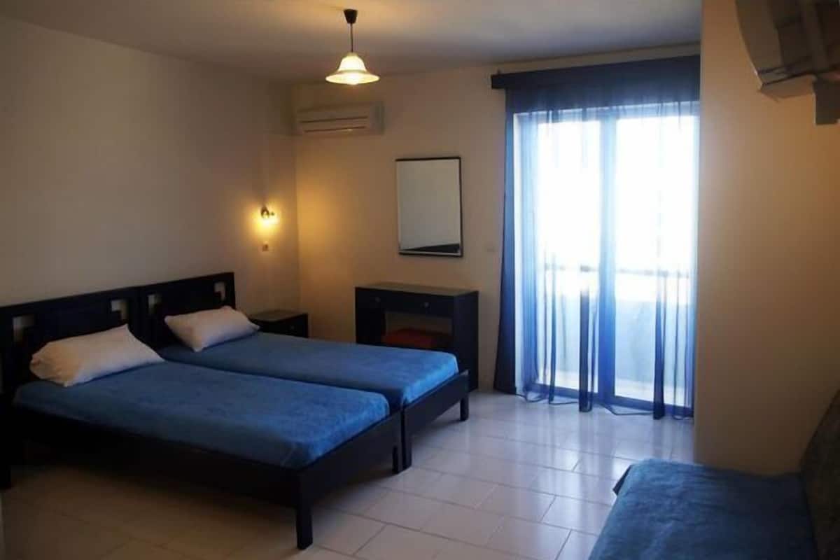 A hotel room with two beds, a nightstand, a mirror, and a window with curtains.