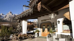 A hotel entrance with a mountain view, outdoor seating, and traditional decor.