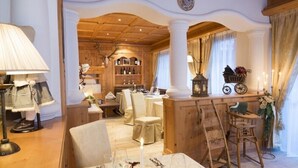 A cozy, well-lit dining area with wooden furniture, a bar area with a vintage bicycle, and a wine rack in the background.