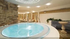 A spa area with a hot tub, stone wall, lounge chairs, and a decorative fountain.