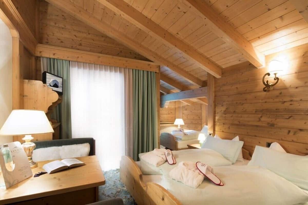 Una habitación tipo cabaña de madera con cama, mesitas de noche, un escritorio y una silla.
