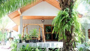 A modern house with a wooden roof, large windows, and a variety of potted plants. - Le Pes Villas (Khanom)