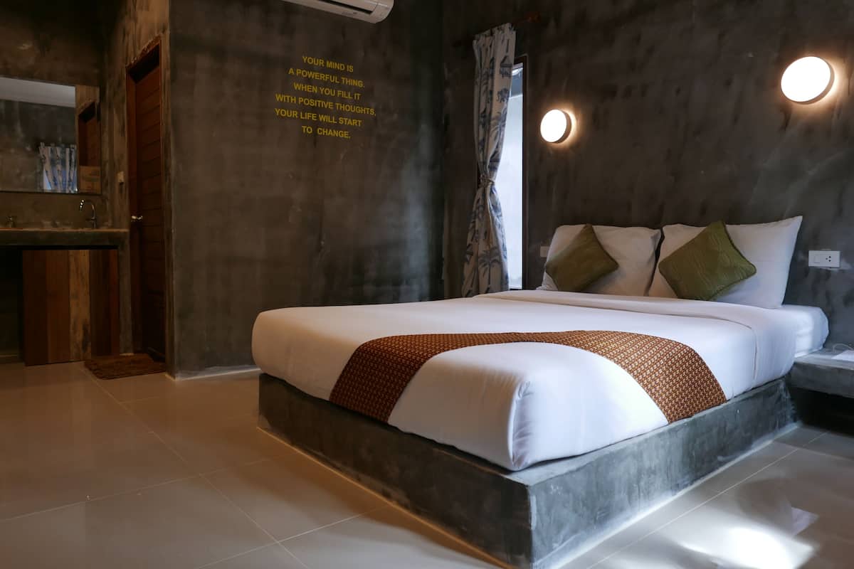 A modern bedroom with a large bed, a built-in bench, a vanity with a mirror, and a motivational quote on the wall.