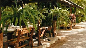 A covered outdoor seating area with wooden benches and potted plants. - Le Pes Villas (Khanom)