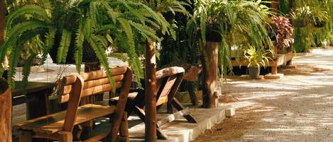 A covered outdoor seating area with wooden benches and potted plants.