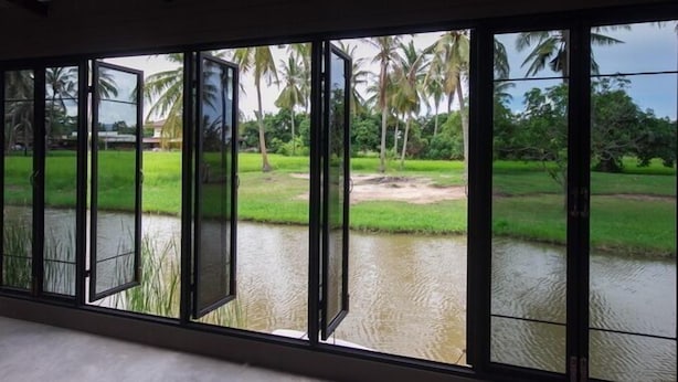 A room with large windows overlooking a water body and greenery. - Cha-Am Country Home (Cha-am)