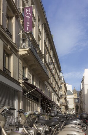 A row of parked scooters in front of a hotel with a sign reading "HOTEL".