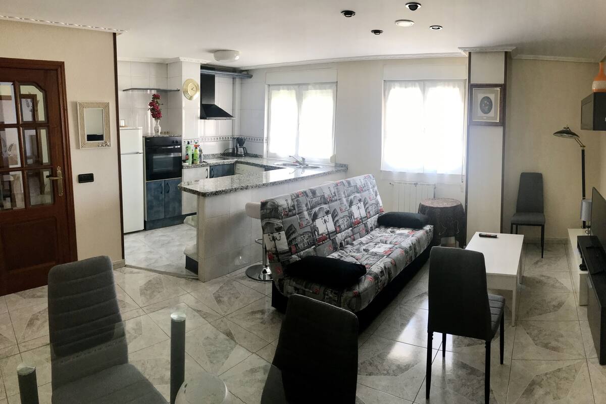 A compact living space with a kitchenette, a sofa, a dining table, and a TV.