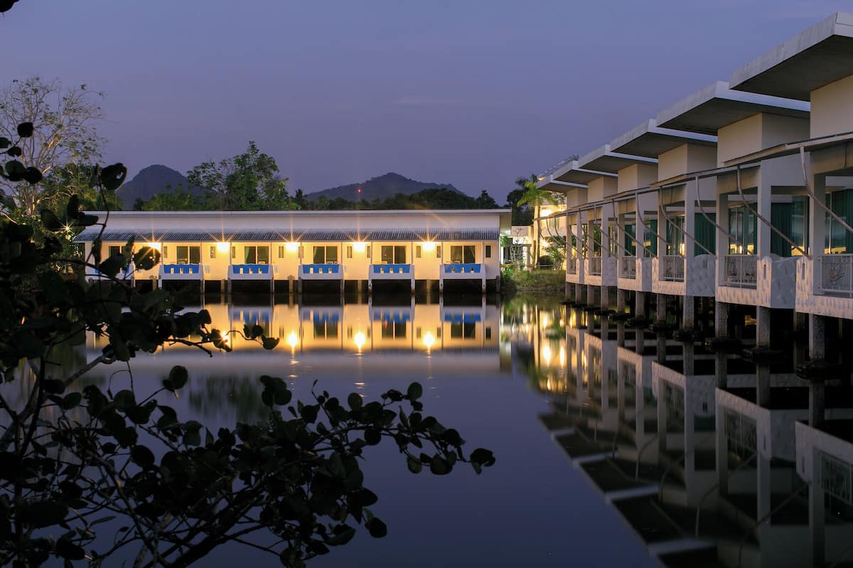 A hotel with a pool reflecting the building and a mountain in the background.
