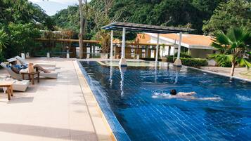 Een buitenzwembad, parasols bij het zwembad en ligstoelen