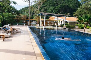 Una piscina al aire libre, sombrillas, sillones reclinables de piscina