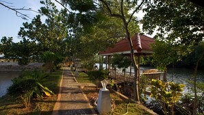 A pathway leading to a gazebo by a lake, surrounded by greenery and trees. - Anavilla Tangke Resort (Khanom)