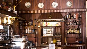 A bar with wooden walls, shelves of liquor bottles, and a coffee machine.