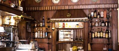 A bar with wooden walls, shelves of liquor bottles, and a coffee machine.