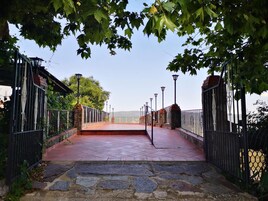 Uma trilha de pedra leva a um portão com grades de metal e postes de luz.