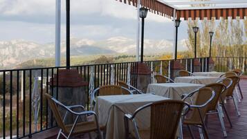 An outdoor patio with tables and chairs, a pergola, and a view of mountains.