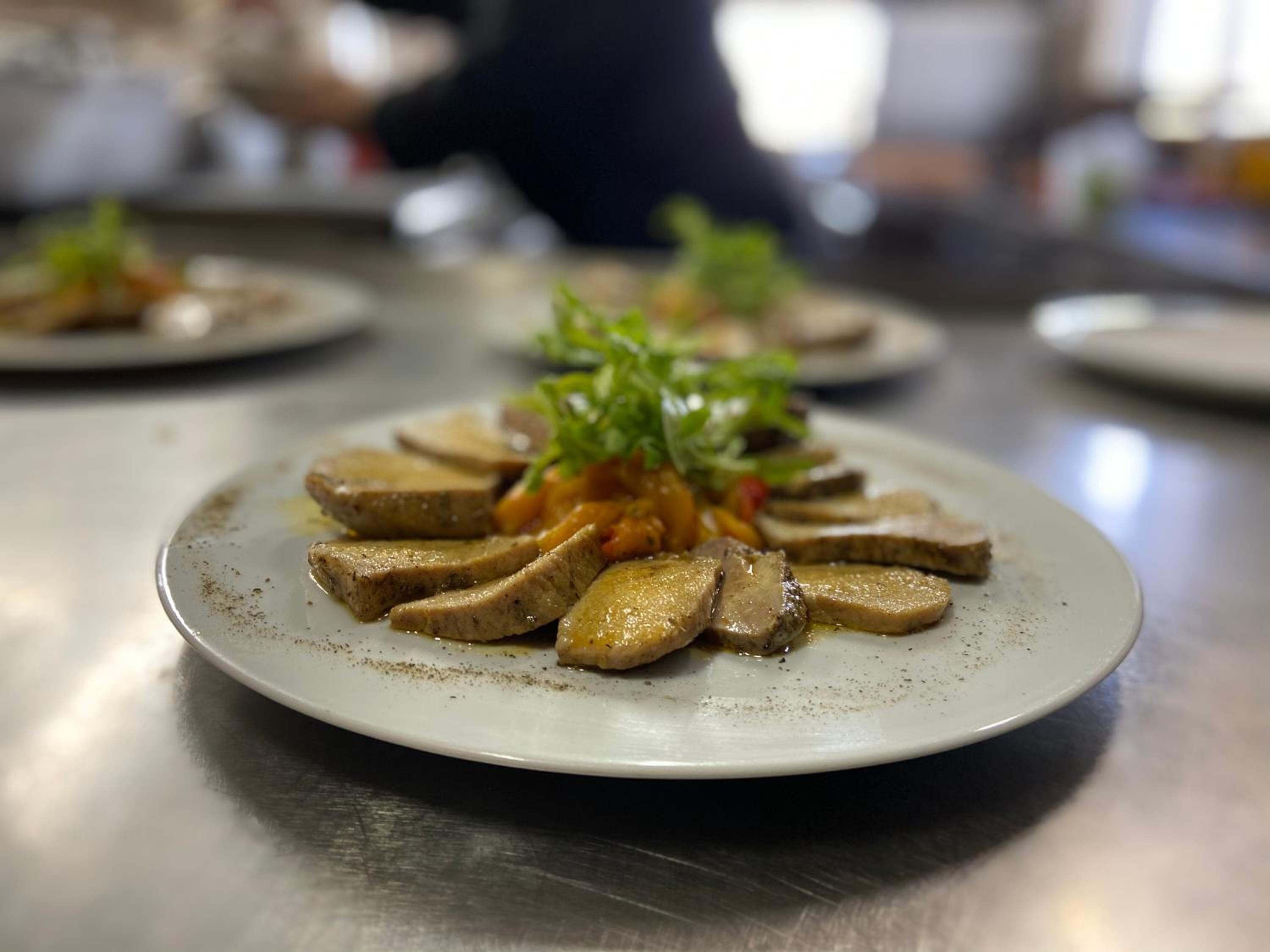 A plate of sliced mushrooms with a garnish of greens, served on a white plate.