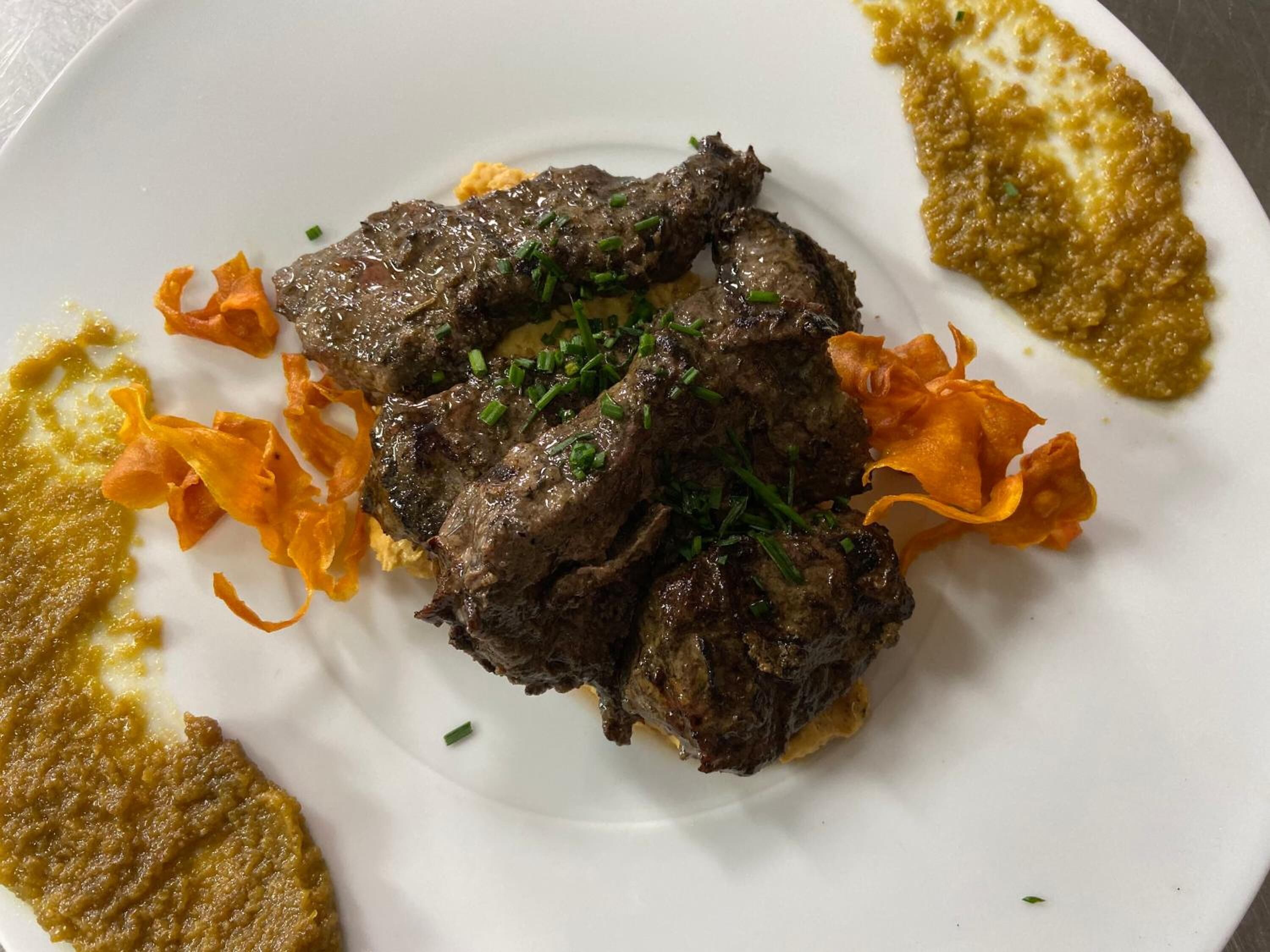 Een bord met vlees, groenten en saus.