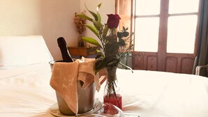 A bed with a metal bucket containing a rose and a glass bottle.