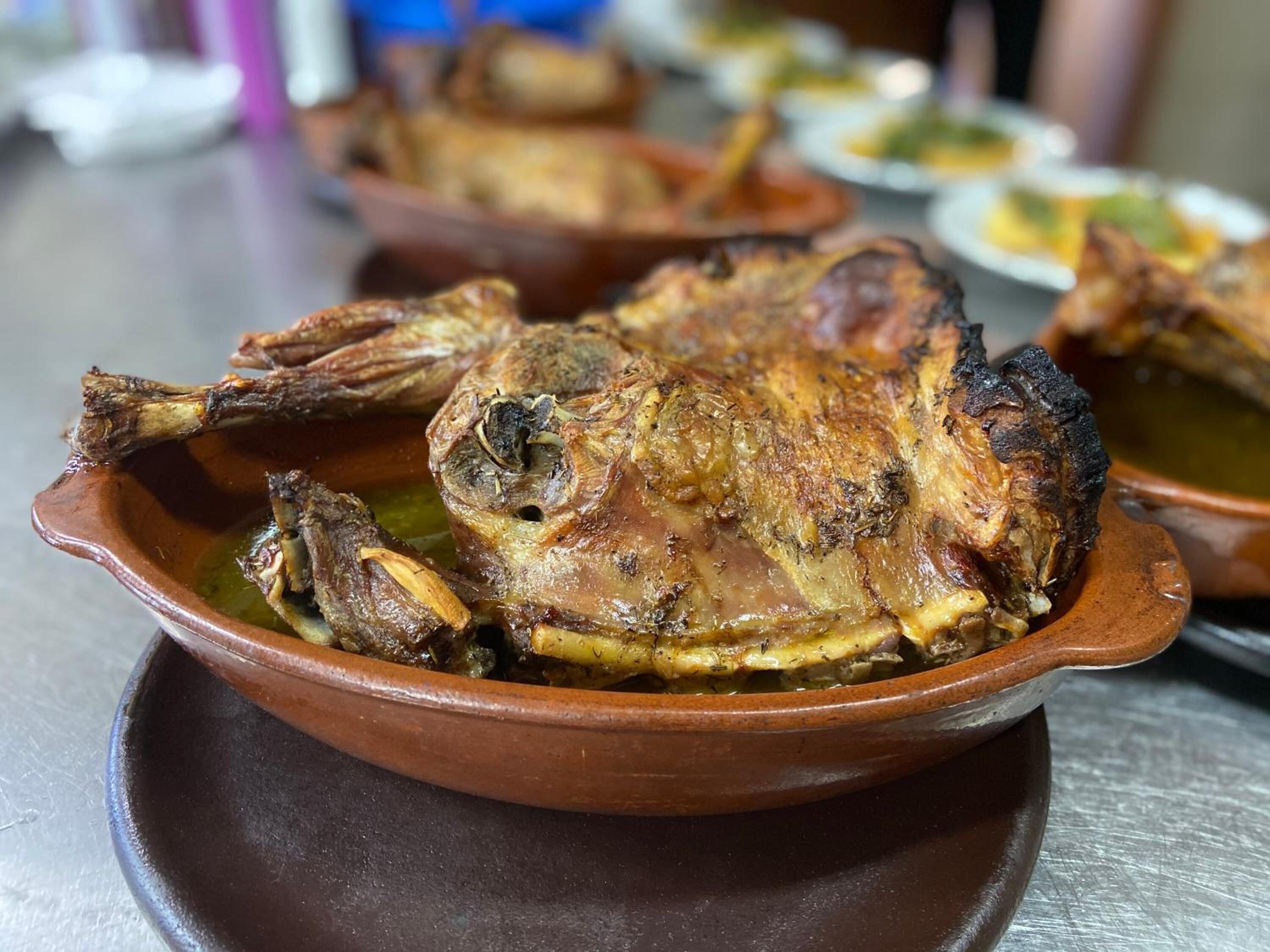 A roasted duck in a clay dish, likely served as a main course.