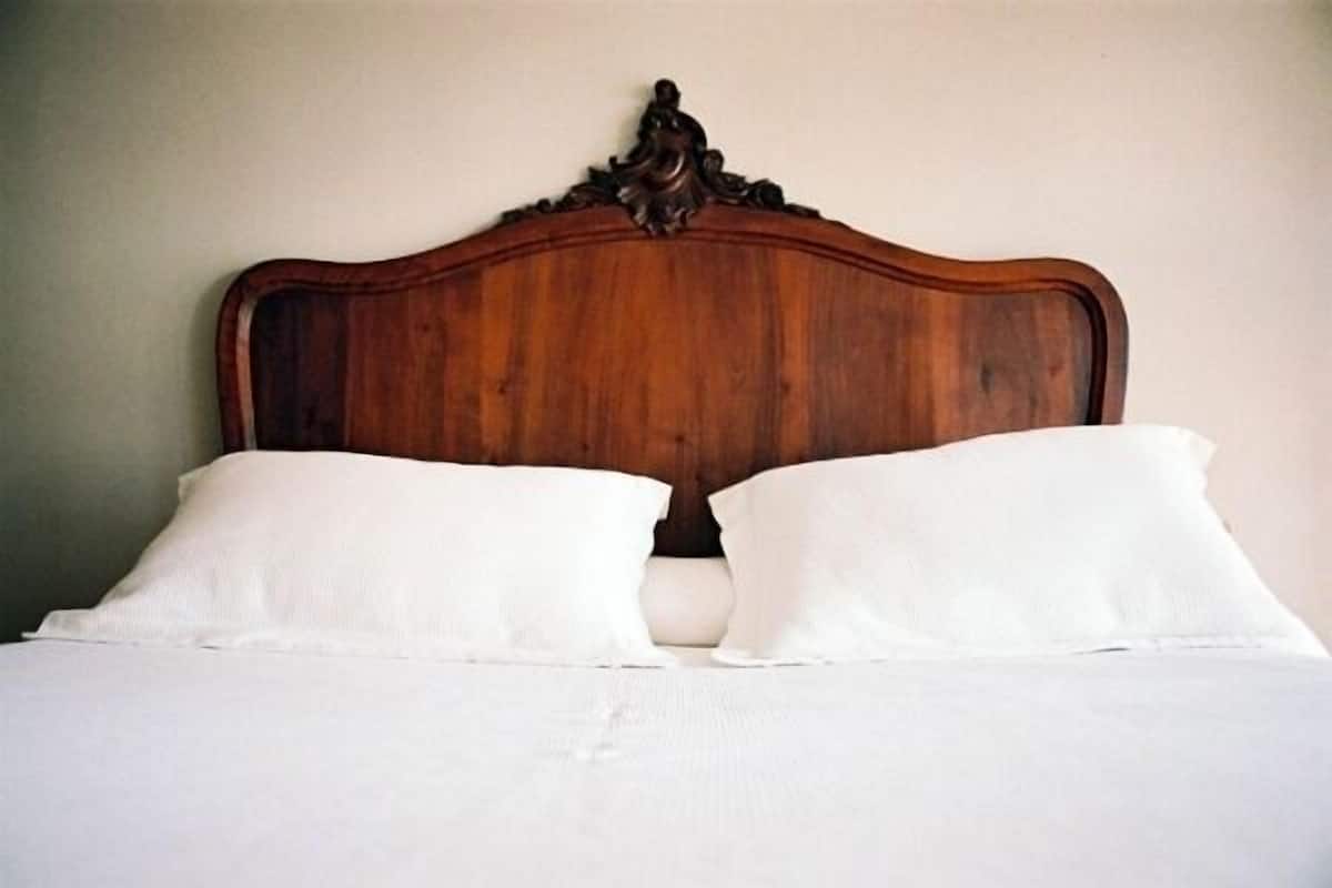 Een bed met een houten hoofdbord en twee witte kussens.