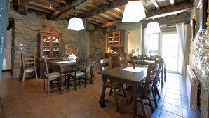 Un comedor rústico con mesa y sillas de madera, paredes de piedra y vigas de madera a la vista.